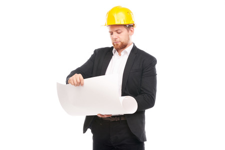 Portrait of architect wearing suit and yellow hardhat holding project plan on white backgroundの写真素材