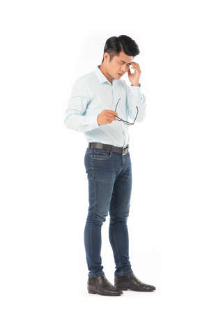 Full length portrait of young Asian man suffering from headache isolated on whiteの写真素材