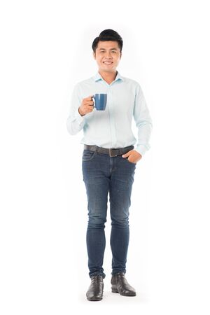 Young Asian man holding mug with hot drink on white backgroundの写真素材