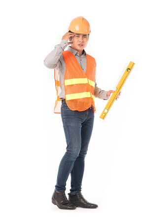 Studio portrait of construction worker in orange waistcoat and hardhat holding levelling tool and building planの写真素材