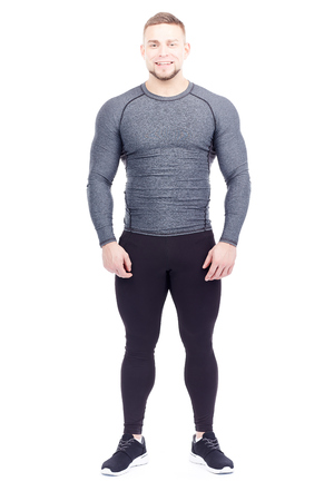 Portrait of handsome well-muscled gym instructor in sports tights and rashguard posing on white backgroundの写真素材