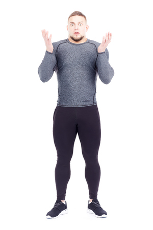 Portrait of handsome well-muscled gym instructor in sports tights and rashguard posing on white backgroundの写真素材
