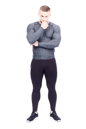 Portrait of handsome well-muscled gym instructor in sports tights and rashguard posing on white backgroundの写真素材
