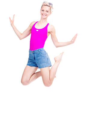 Vertical full length studio portrait of cheerful young Caucasian woman wearing summer outfit jumping, white backgroundの写真素材