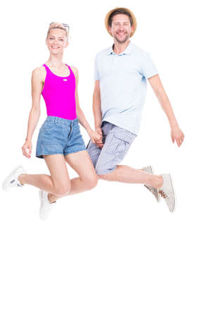 Vertical full length studio portrait of cheerful young adult Caucasian man and woman jumping together, white backgroundの写真素材