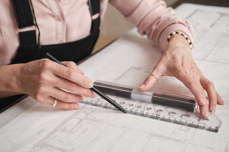 Close-up of unrecognizable female hands in ring using ruler and pencil and creating technical drawingの写真素材