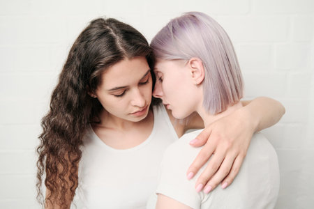 Calm young brunette lesbian woman in white tshirt hugging girlfriend while comforting her
