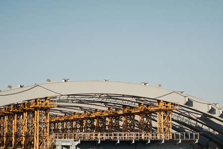 Unfinished city bridge: yellow metal frames supporting arch structureの写真素材
