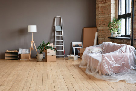 Horizontal no people shot of empty spacious loft living room in modern apartment with boxes, ladder, sofa and various thingsの写真素材