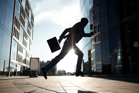 Silhouette of African American white-collar worker with case running towards modern office building...
