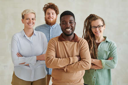 Successful marketing team of young multi-ethnic specialists standing with crossed arms against isolated backgroundの写真素材