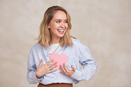 Horizontal medium portrait of happy lovely young woman wearing casual outfit holding paper pink...