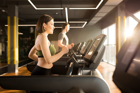 Young healthy people have cardio training on treadmill during sports training in gym