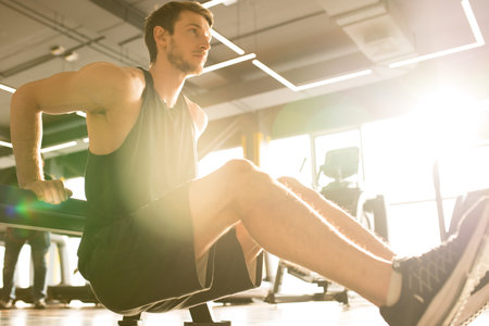 Handsome athlete working out in gym doing biceps exercises in health club
