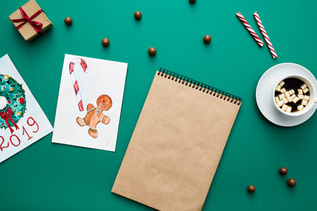 Christmas background: high angle view of Christmas cards, cocoa with marshmallows, blank sketchpad...