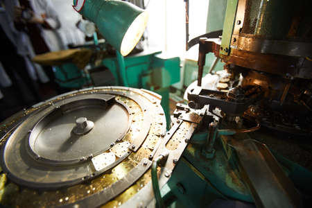 Close-up of production line of gear parts for quartz clocks, round metal rotating part with golden piecesの写真素材