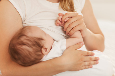Mother holding hand of adorable little baby sleeping in her arms with love and tender