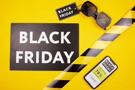 High angle view of Black Friday banner and sunglasses with tag on yellow background, online website...