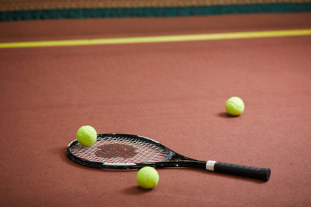 Close-up of modern tennis equipment scattered on floor of indoor tennis court, background of sports...