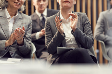 Close-up of business people in formal jackets sitting in auditorium and clapping hands while welcoming coach at training classの写真素材
