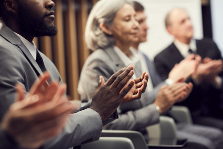 Close-up of multi-ethnic business people in formalwear sitting in row and applauding after...