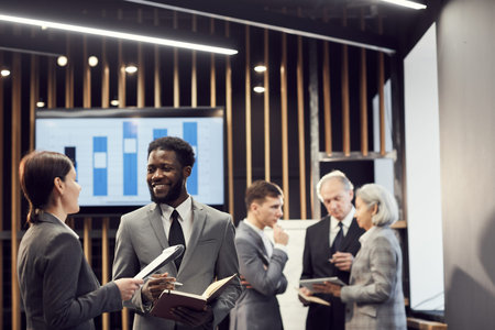 Business people in suits standing in hall and discussing ideas while building partnership at...