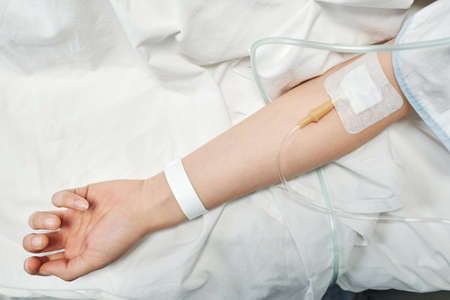 From above view shot of unrecognizable female patient receiving medication fluids through IV lineの写真素材