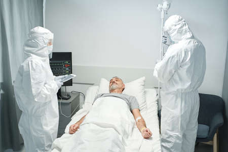 Two medical specialists wearing personal protection equipment working with patient in Infectious Disease departmentの写真素材