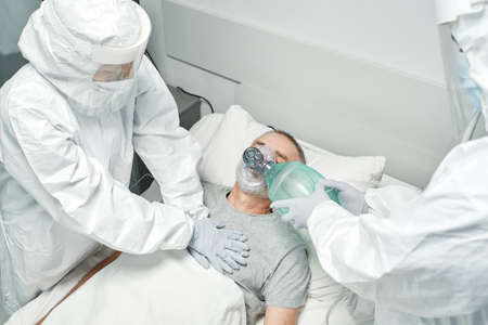 High angle view shot of unrecognizable doctors wearing protective suits rescuing mature man performing CPRの写真素材