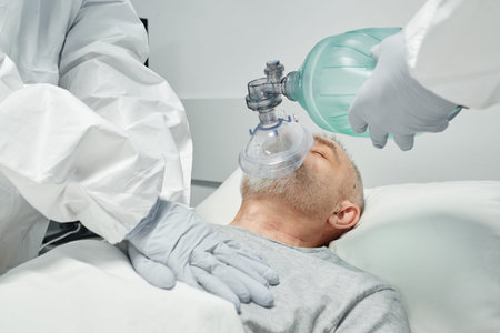 Unrecognizable professional medical workers wearing personal protection equipment doing CPR for...