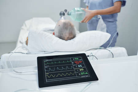 Unrecognizable doctor saving life of mature patient performing artificial ventilation, selective focus on foreground shotの写真素材