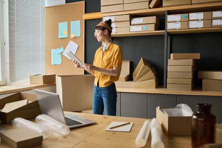 Young woman using digital tablet to distributing parcels for shipping, working in warehouseの写真素材