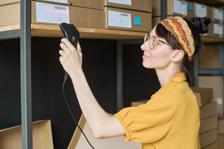 Young woman scanning parcels on shelf with scanner in warehouse