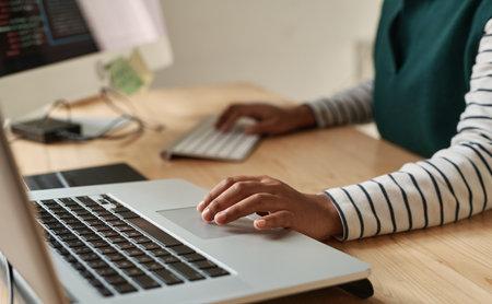 Hand of young black woman over laptop touchpad during network or creation of new website while sitting by workplace in officeの写真素材