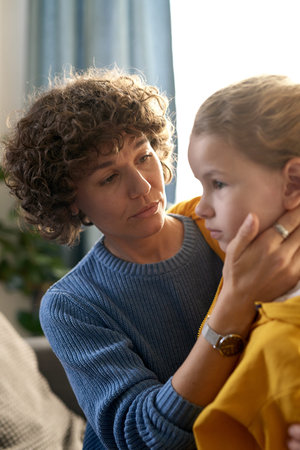 Caring mother embracing and comforting her child during their conversation at home