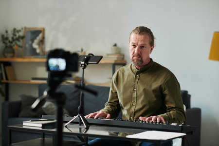 Music teacher using camera for online lesson while playing piano at table at homeの写真素材