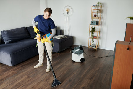 Professional cleaning service worker vacuuming the floor in the roomの写真素材
