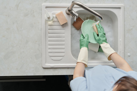 Top view of professional cleaner washing dishes in sink during work in the kitchenの写真素材