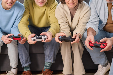 Close-up of family of four using joysticks to play game console together at homeの写真素材