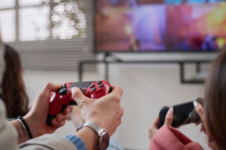 Close-up of mom and daughter pushing buttons on joysticks while playing video game togetherの写真素材