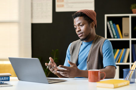 African American student discussion topic during video call with teacher while sitting at table with laptopの写真素材