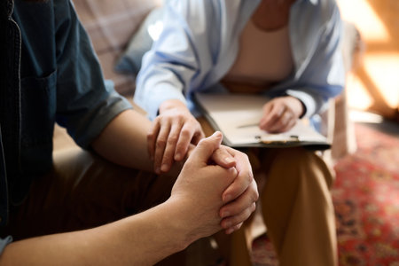 Close-up of psychologist supporting her patient holding his hand during session in officeの写真素材
