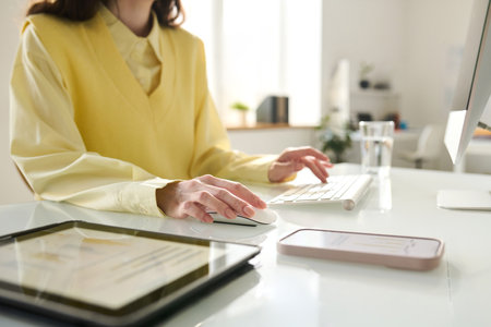 Close-up of young woman working on computer while sitting at her workplace in officeの写真素材