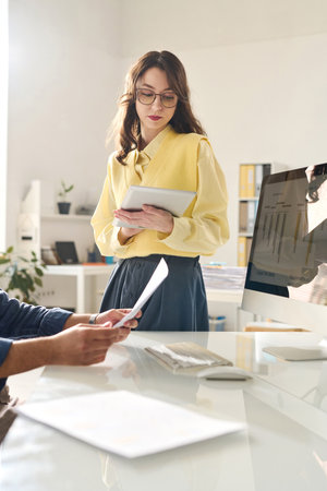 Young businesswoman using digital tablet at her work while standing in officeの写真素材