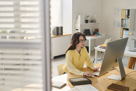 Young businesswoman concentrating on her work on computer while working at her workplace in officeの写真素材