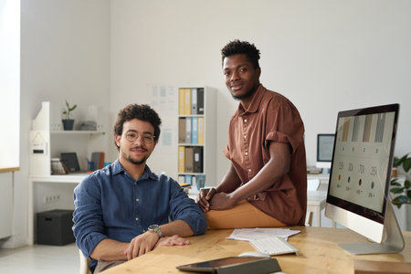 Portrait of young multiethnic colleagues looking at camera while working together in officeの写真素材