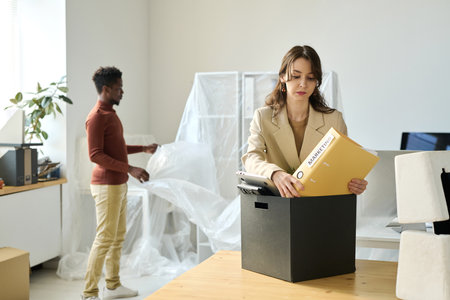 Young businesswoman packing documents in box during the moveの写真素材