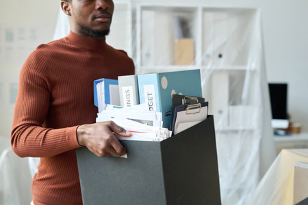 African American man carrying box with folders during movement in new officeの写真素材