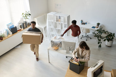 High angle view of business people packing things and furniture while moving in new officeの写真素材