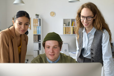 Businesswomen discussing presentation on computer together with their colleague who sitting in front of computerの写真素材